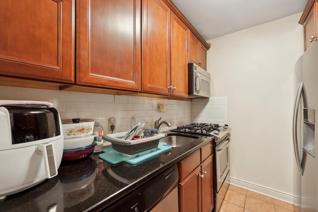 500 Central Ave Unit 1713, Union City, NJ 07087 - kitchen featuring light tile patterned flooring, stainless steel appliances, tasteful backsplash, brown cabinetry, and dark stone countertops