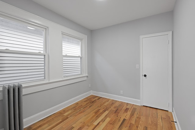 unfurnished room featuring light hardwood / wood-style floors and radiator heating unit