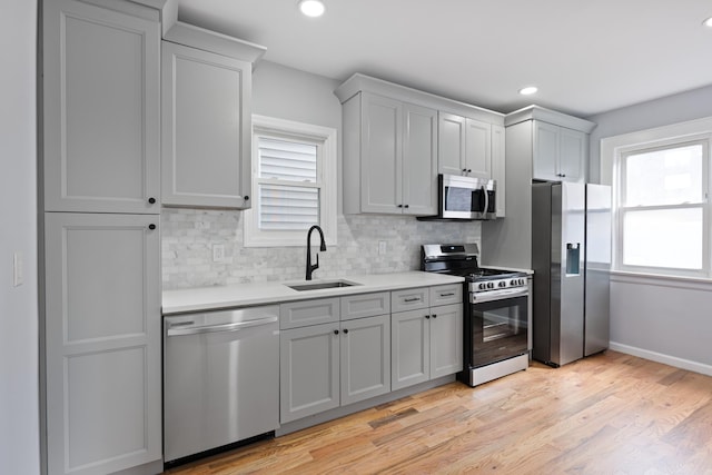 kitchen with sink, stainless steel appliances, light hardwood / wood-style floors, and plenty of natural light