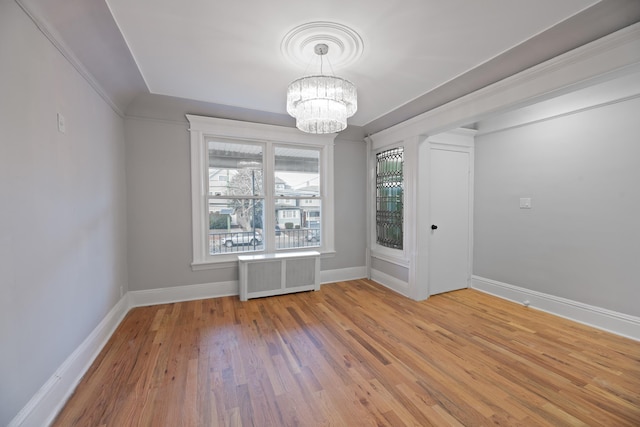 empty room with wood-type flooring, a chandelier, and radiator heating unit