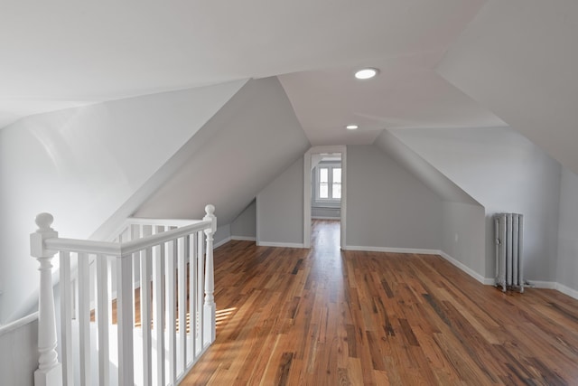 additional living space featuring dark wood-type flooring, vaulted ceiling, and radiator