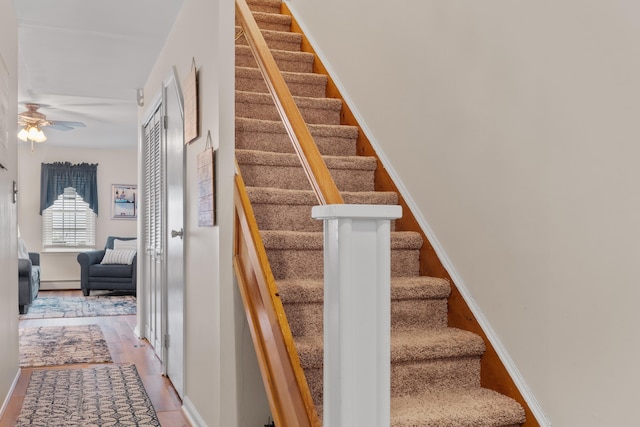 27 E 34th St, Bayonne, NJ 07002 - staircase with a ceiling fan, wood finished floors, and a baseboard heating unit