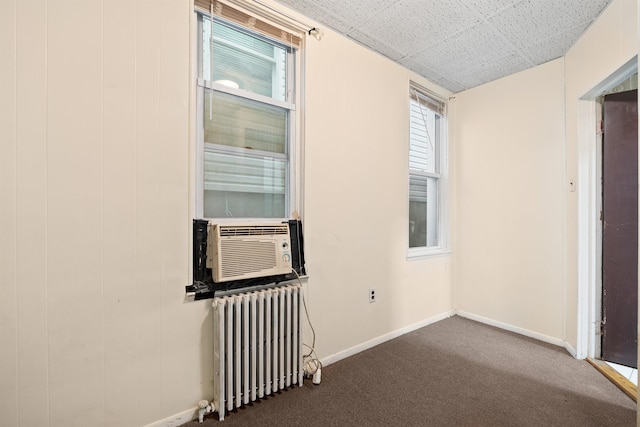 spare room featuring dark colored carpet, radiator heating unit, cooling unit, and baseboards