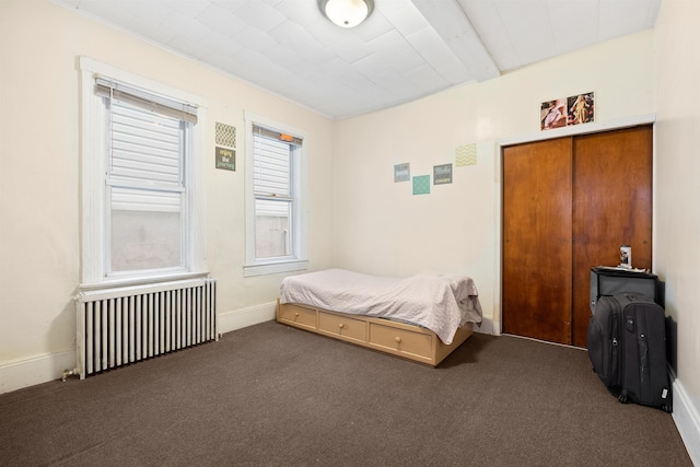 bedroom featuring radiator, baseboards, and dark colored carpet