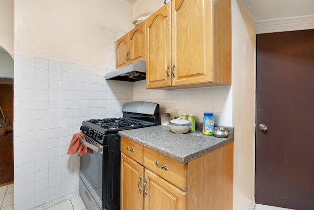 kitchen with gas range oven, light tile patterned flooring, tile walls, and under cabinet range hood