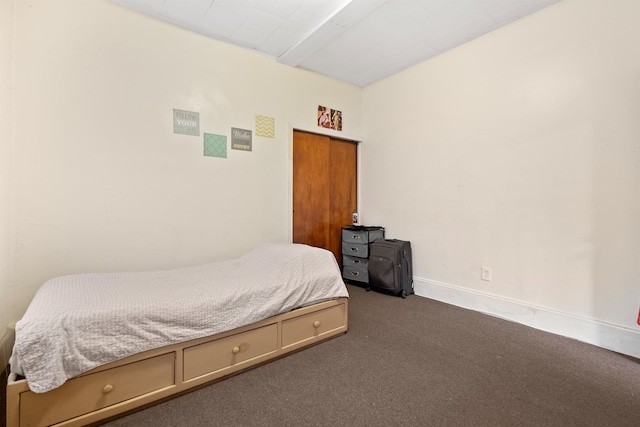 bedroom featuring dark carpet and baseboards