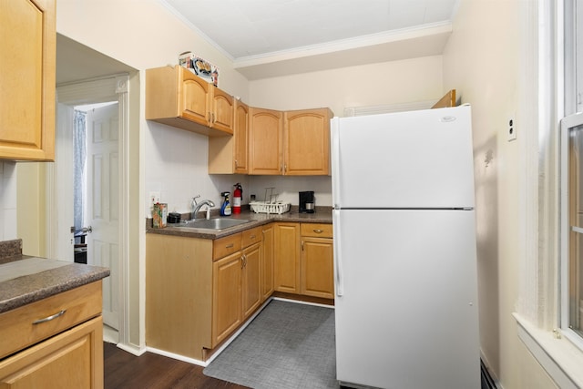 kitchen featuring decorative backsplash, dark countertops, freestanding refrigerator, crown molding, and a sink