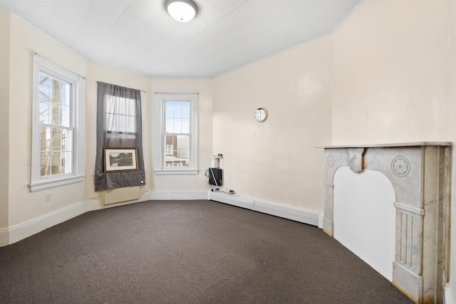 spare room featuring ornamental molding, dark colored carpet, and baseboards