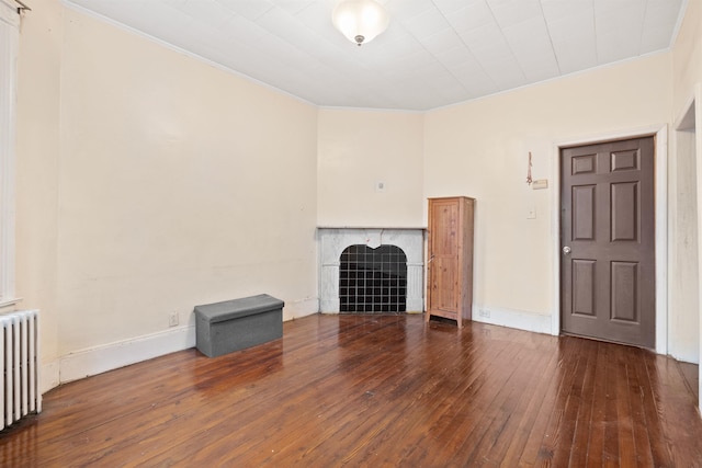 unfurnished living room with radiator, baseboards, dark wood finished floors, and a tile fireplace