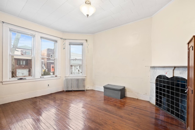 unfurnished living room with dark wood-style floors, radiator heating unit, a fireplace, and baseboards