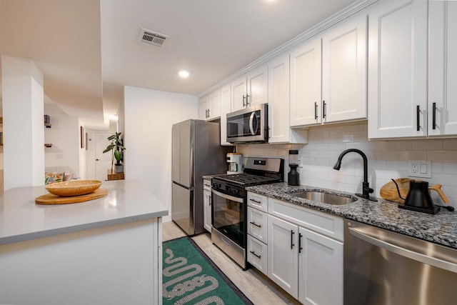 kitchen with sink, kitchen peninsula, white cabinets, and appliances with stainless steel finishes