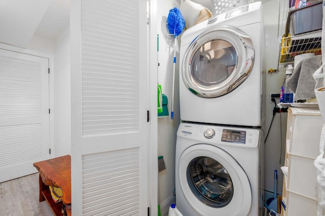 laundry area with stacked washer and dryer and light hardwood / wood-style flooring