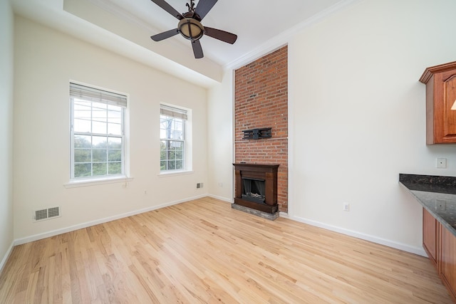 unfurnished living room with ceiling fan, ornamental molding, a fireplace, and light hardwood / wood-style flooring