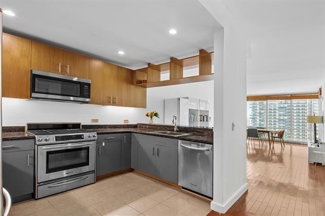 1 Shore Ln Unit 1805, Jersey City, NJ 07310 - kitchen featuring appliances with stainless steel finishes, dark stone countertops, a sink, brown cabinetry, and recessed lighting