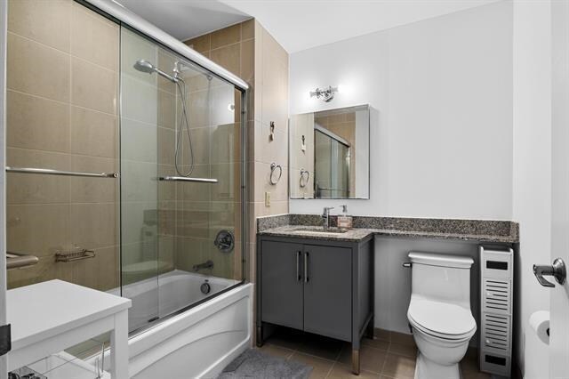 1 Shore Ln Unit 1805, Jersey City, NJ 07310 - full bath with shower / bath combination with glass door, tile patterned flooring, toilet, and vanity