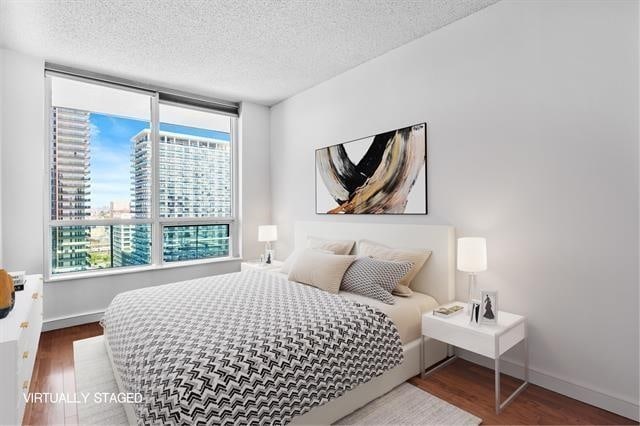 1 Shore Ln Unit 1805, Jersey City, NJ 07310 - bedroom featuring wood finished floors, multiple windows, a textured ceiling, and baseboards