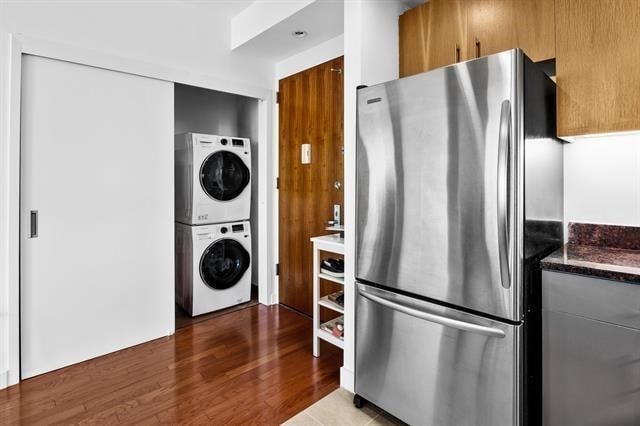 1 Shore Ln Unit 1805, Jersey City, NJ 07310 - kitchen featuring freestanding refrigerator, estacked washer and dryer, wood finished floors, and dark stone counters
