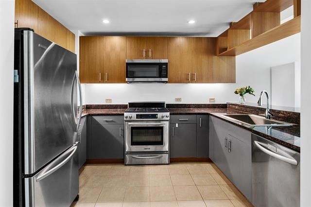 1 Shore Ln Unit 1805, Jersey City, NJ 07310 - kitchen with appliances with stainless steel finishes, a sink, open shelves, brown cabinets, and dark stone countertops