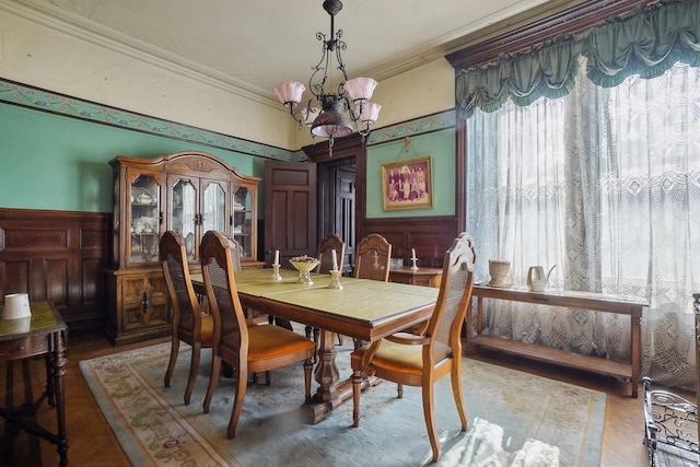 dining space with ornamental molding, a chandelier, wainscoting, and wood finished floors