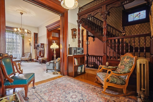 living area with wallpapered walls, stairs, crown molding, carpet flooring, and a chandelier