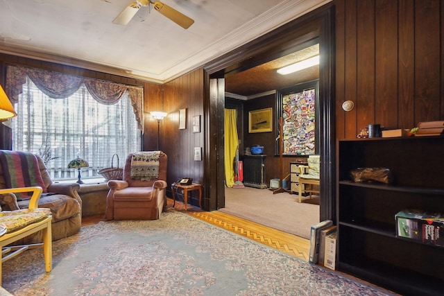 living area with a ceiling fan, crown molding, wood walls, and wood finished floors