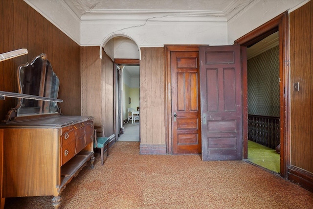 interior space featuring arched walkways, wooden walls, and crown molding