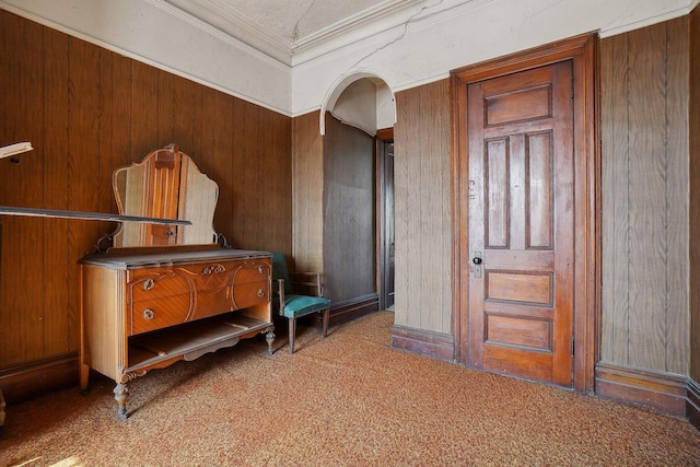 interior space with arched walkways, carpet floors, ornamental molding, and wooden walls