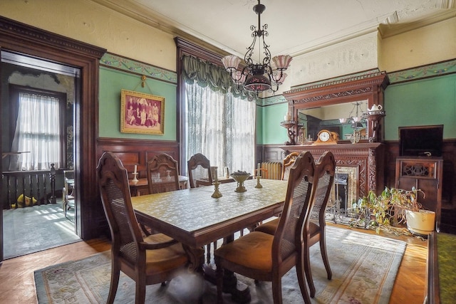 dining area with wainscoting, crown molding, and an inviting chandelier