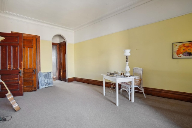 carpeted dining room with ornamental molding, arched walkways, and baseboards