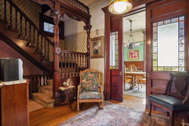 living area with ornamental molding, wainscoting, wood finished floors, and wallpapered walls