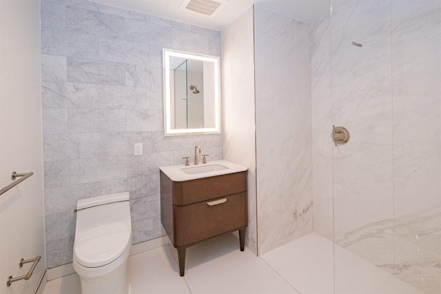 bathroom with toilet, tile patterned flooring, tile walls, and vanity