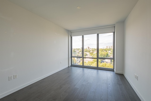 unfurnished room with a wall of windows and dark hardwood / wood-style floors