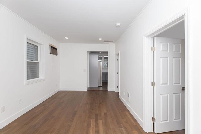 empty room with ornamental molding, dark wood-type flooring, baseboards, recessed lighting, and an AC wall unit