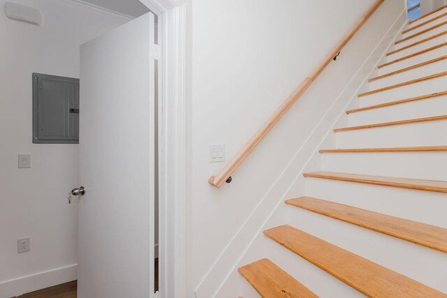 stairs with electric panel, baseboards, and wood finished floors