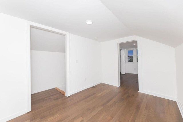 additional living space with wood finished floors, vaulted ceiling, and baseboards