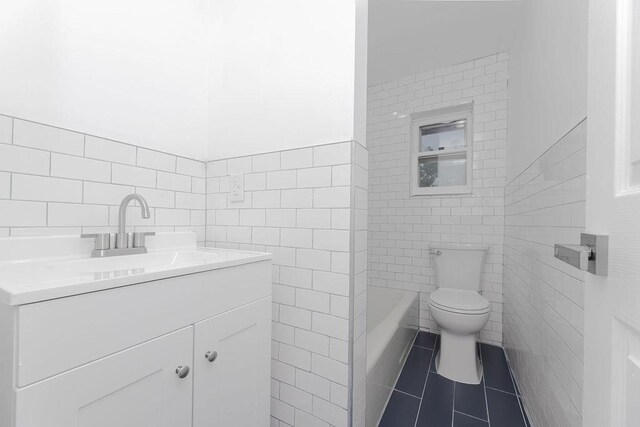 bathroom featuring tile walls, toilet, vanity, a bath, and tile patterned floors