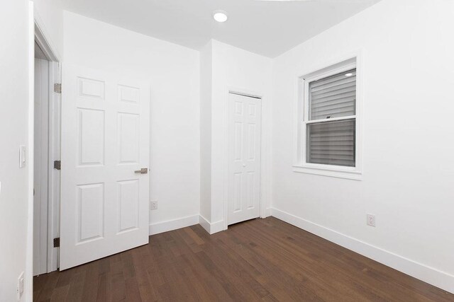 unfurnished bedroom featuring dark wood finished floors, baseboards, a closet, and recessed lighting