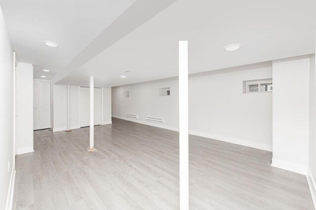 finished below grade area featuring light wood-style flooring, baseboards, and recessed lighting