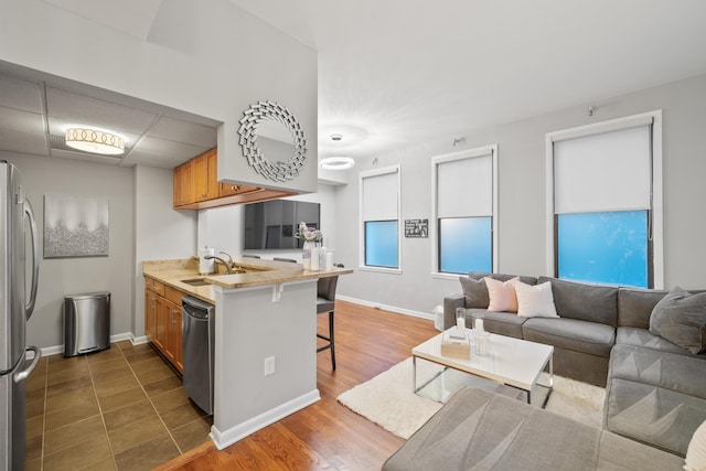 kitchen featuring sink, dark wood-type flooring, kitchen peninsula, a kitchen bar, and appliances with stainless steel finishes