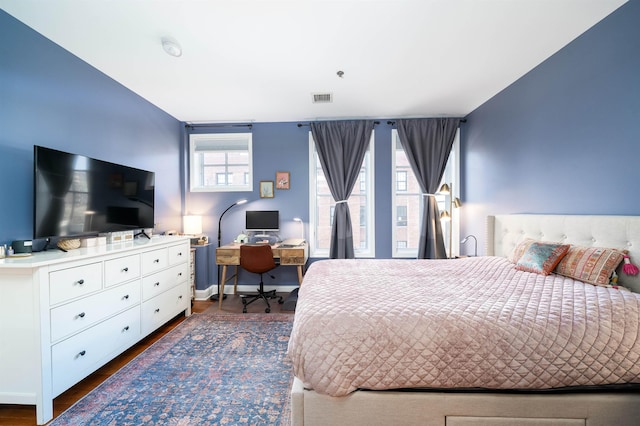 bedroom with visible vents, baseboards, and wood finished floors