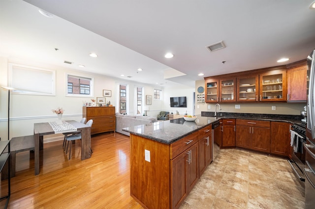 kitchen with dishwashing machine, dark stone countertops, glass insert cabinets, and visible vents