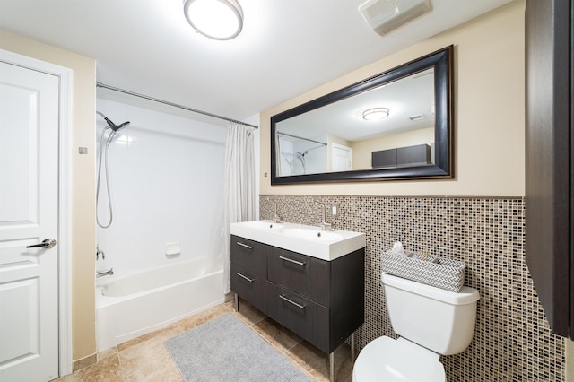 bathroom featuring visible vents, toilet, shower / tub combo with curtain, a sink, and tile walls