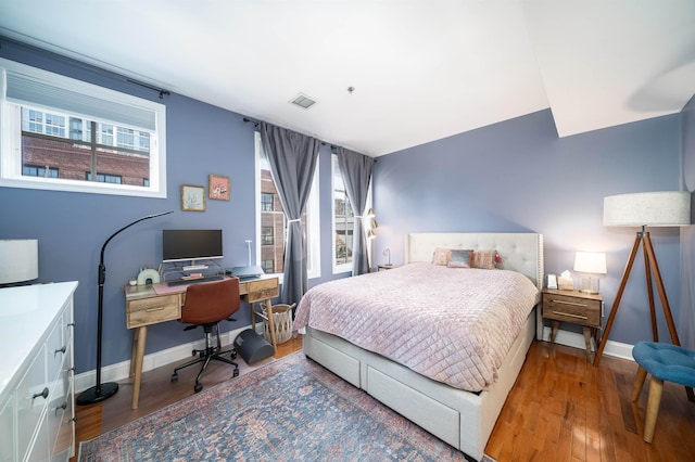 bedroom featuring multiple windows, wood finished floors, visible vents, and baseboards