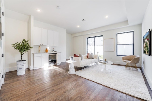 living room featuring indoor wet bar, beverage cooler, and dark hardwood / wood-style flooring