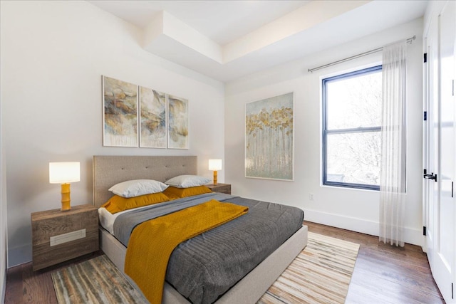 bedroom featuring hardwood / wood-style flooring and a raised ceiling