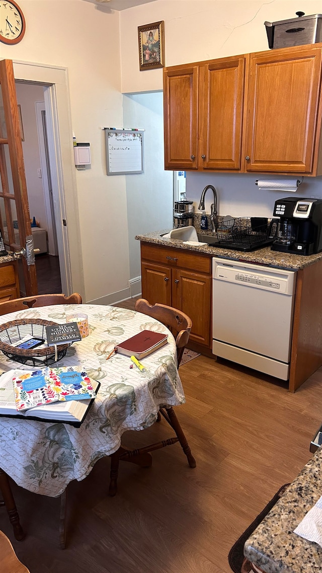 kitchen featuring white dishwasher, hardwood / wood-style flooring, sink, and stone countertops