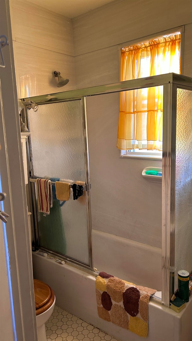 bathroom with toilet, tile patterned flooring, and shower / bath combination with glass door