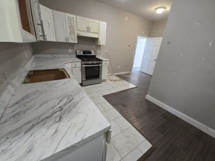 kitchen featuring stainless steel range, white cabinets, and sink