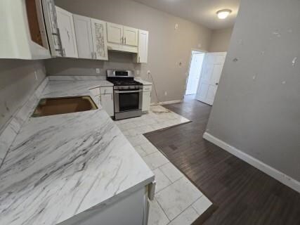 529 Communipaw Ave, Jersey City, NJ 07304 - kitchen featuring gas stove, white cabinetry, dark wood-style flooring, and under cabinet range hood