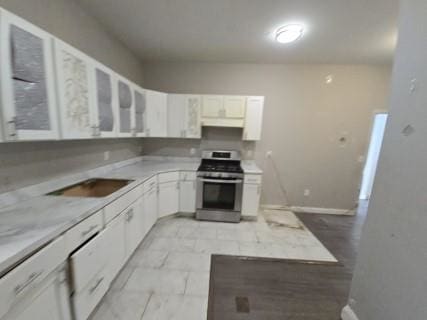 529 Communipaw Ave, Jersey City, NJ 07304 - kitchen with stainless steel range oven, white cabinets, light countertops, glass insert cabinets, and range hood